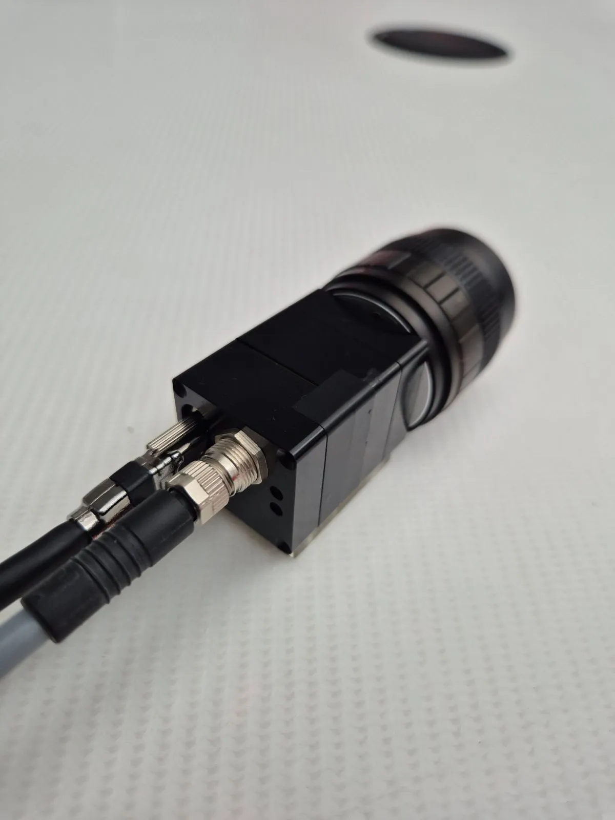 Close-up of the HSCAM NANO prototype's lens mount and cable connectors on a lab bench.